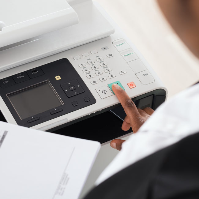 Close-up Of Young Businesswoman Hand Operating Printer In Office