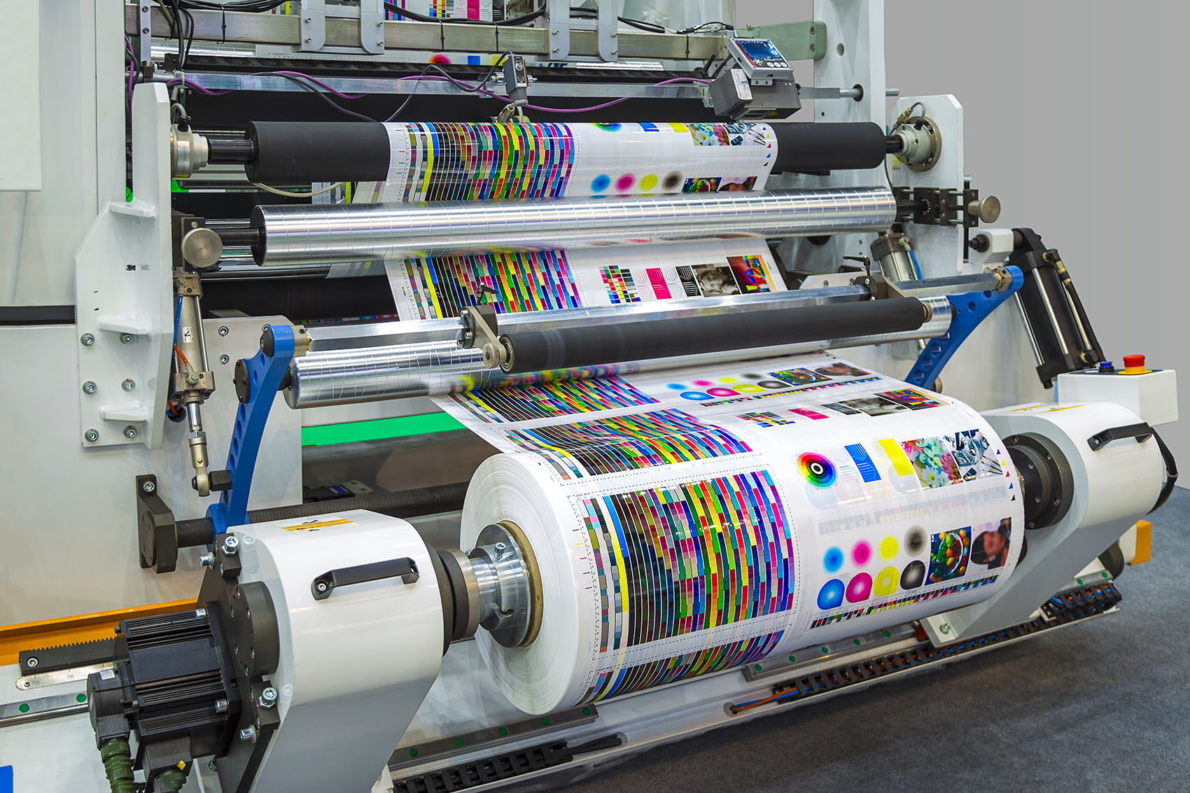 Large offset printing press or magazine running a long roll off paper in production line of industrial printer machine.