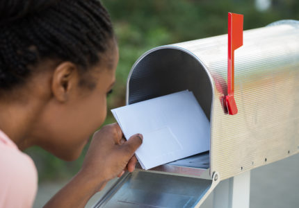Close-up Of Woman Putting Letter In Mailbox