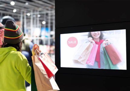 A man and a woman look at digital signage in a clothing store.